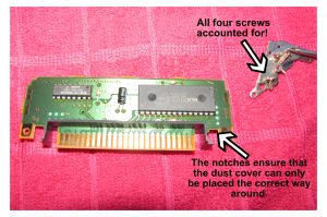 Image of PCB with dust cover, showing notches and screws secured by a magnet.